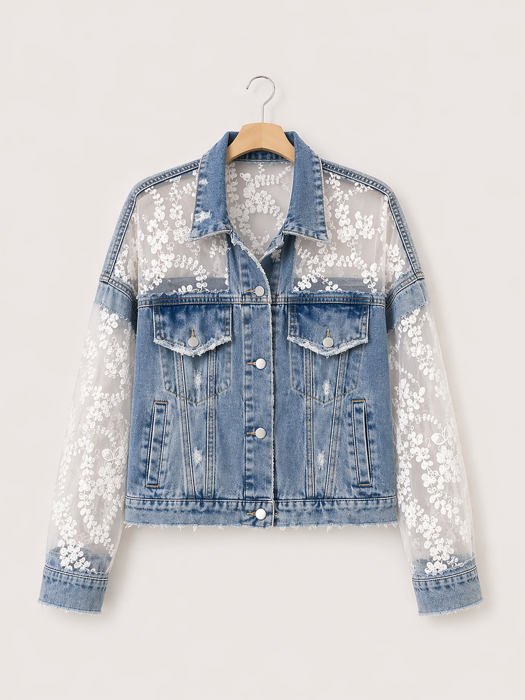 Denim jacket with lace and sequin sleeves on a hanger against a white background