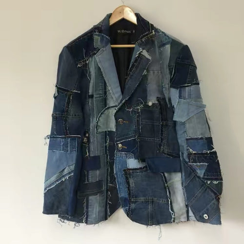 Patchwork denim jacket on a wooden hanger against a plain background