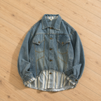 A light blue denim jacket with a striped lining, laid flat on a light wood floor.