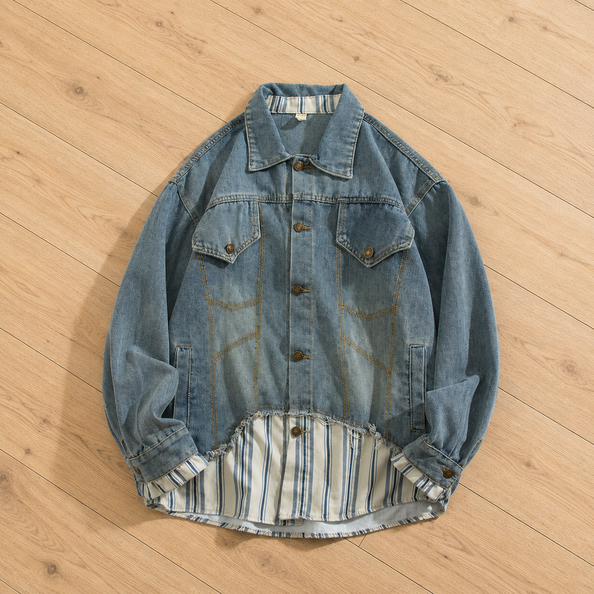 A light blue denim jacket with a striped lining, laid flat on a light wood floor.
